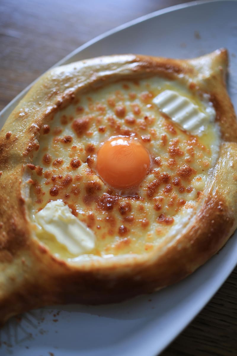 Primer plano de un khachapuri de Adjaria con huevo y queso