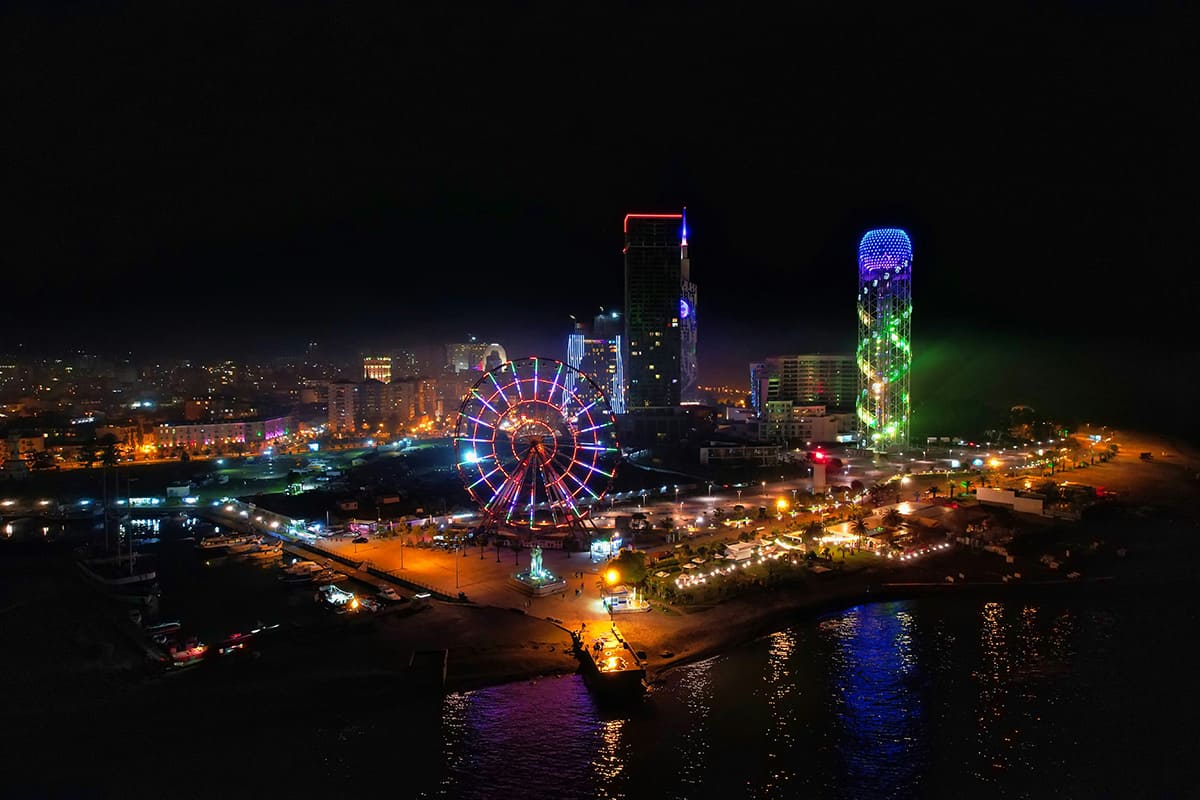 Horizonte de Batumi por la noche, con la noria iluminada y edificios modernos