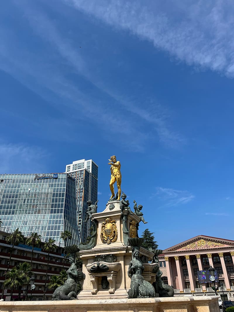 La estatua de la Plaza de Europa en Batumi, rodeada de edificios históricos y bajo un cielo azul