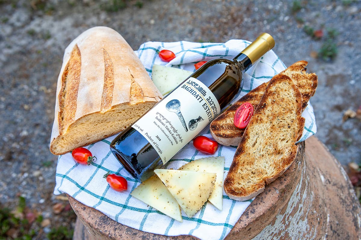 Vino georgiano con pan y queso sobre una mesa