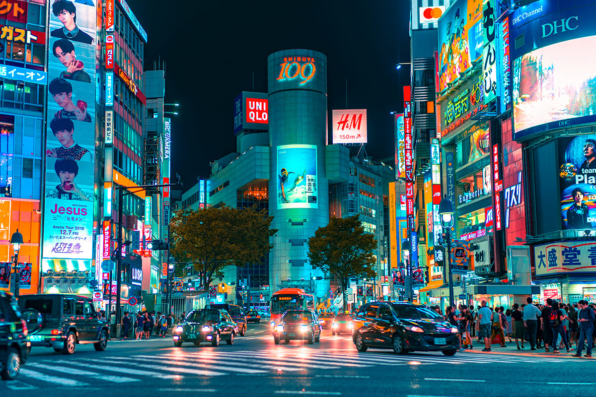 Shibuya Crossing at night with neon lights and busy traffic in Tokyo Japan