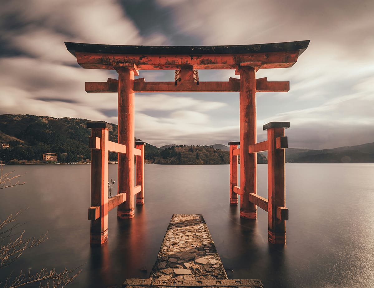 Red torii gate standing in a lake with mountains in Japan