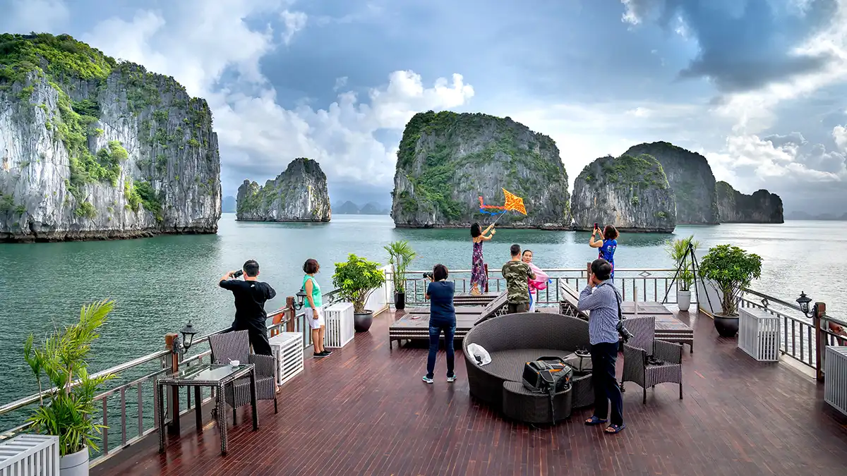 Travelers on a Ha Long Bay cruise deck with limestone islands in the background