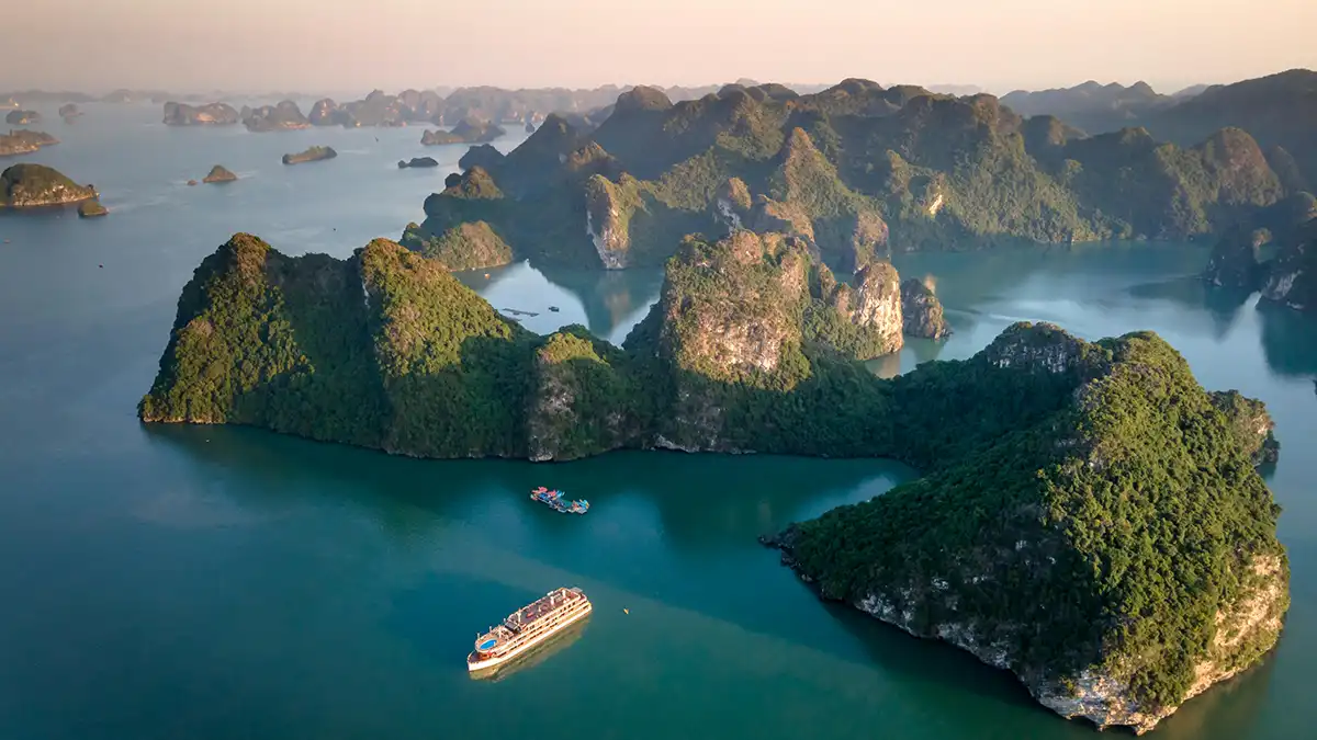Cruise boat sailing among limestone islands in Ha Long Bay