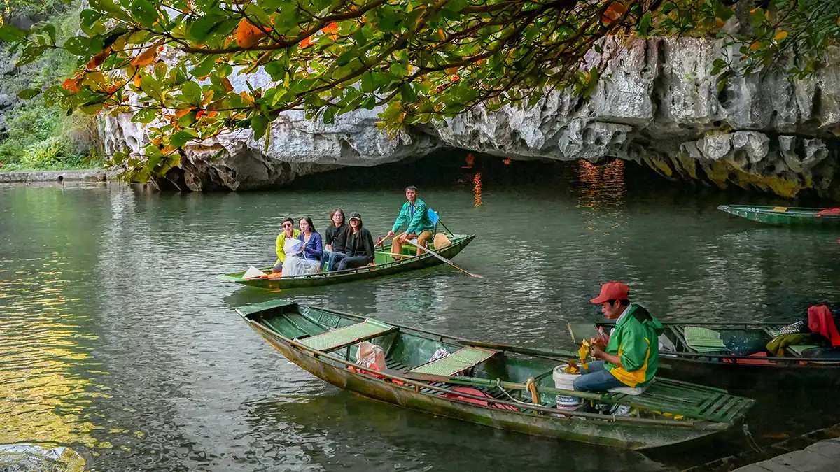 Small boat passing through limestone cliffs on a Trang An boat tour in Ninh Binh