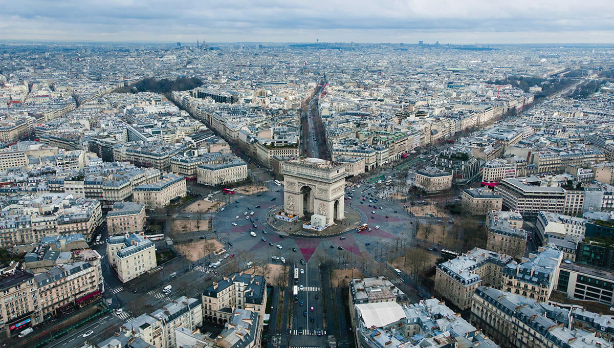Aerial view of Arc de Triomphe with surrounding roads and Paris cityscape