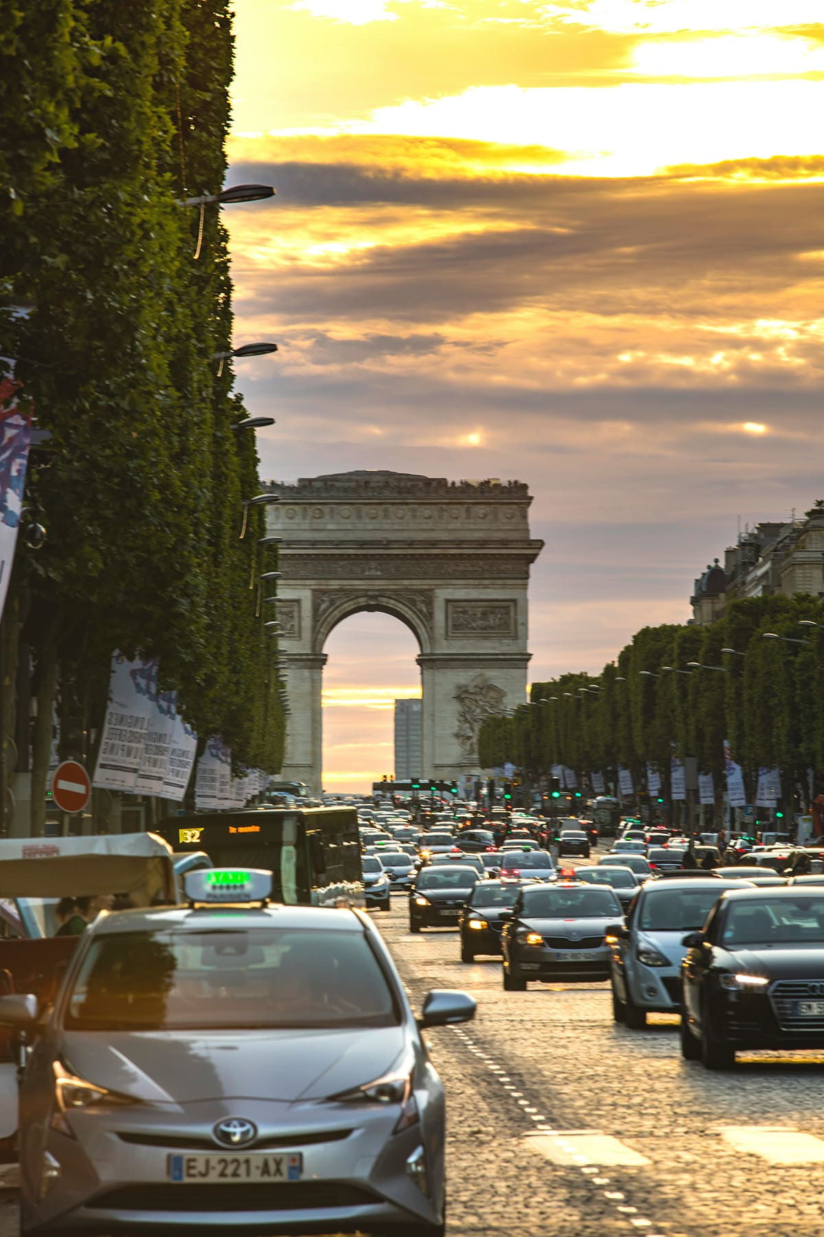 Arc de Triomphe at end of Champs Elysees with traffic during sunset in Paris