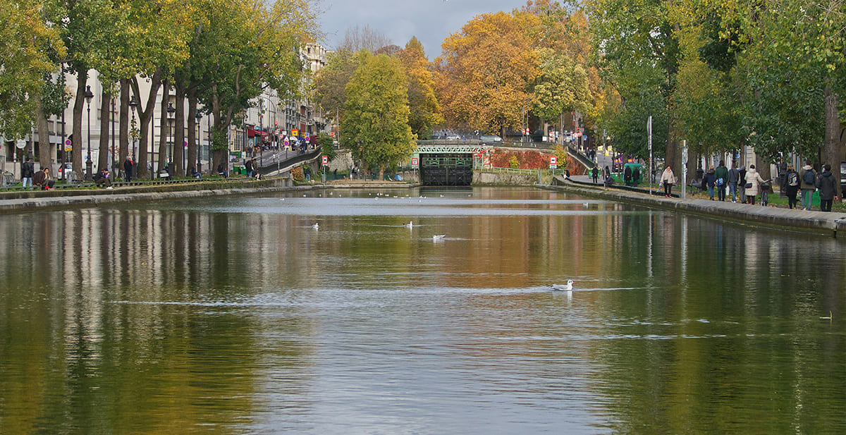 Canal Saint-Martin in Paris with metal bridge and autumn leaves by the water