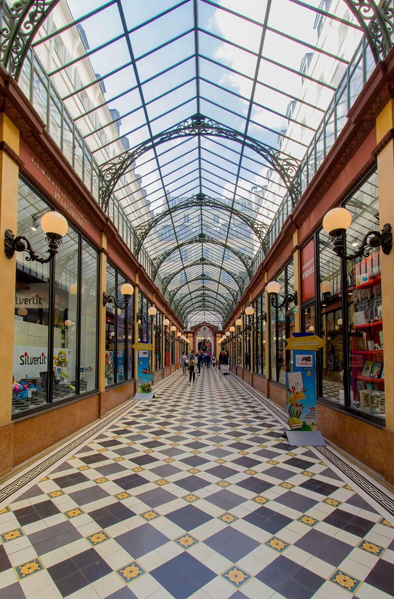 Interior of covered passage in Paris with glass ceiling and shops