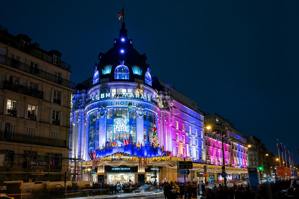 Le BHV Marais shopping center in Paris lit up at night with colorful lights