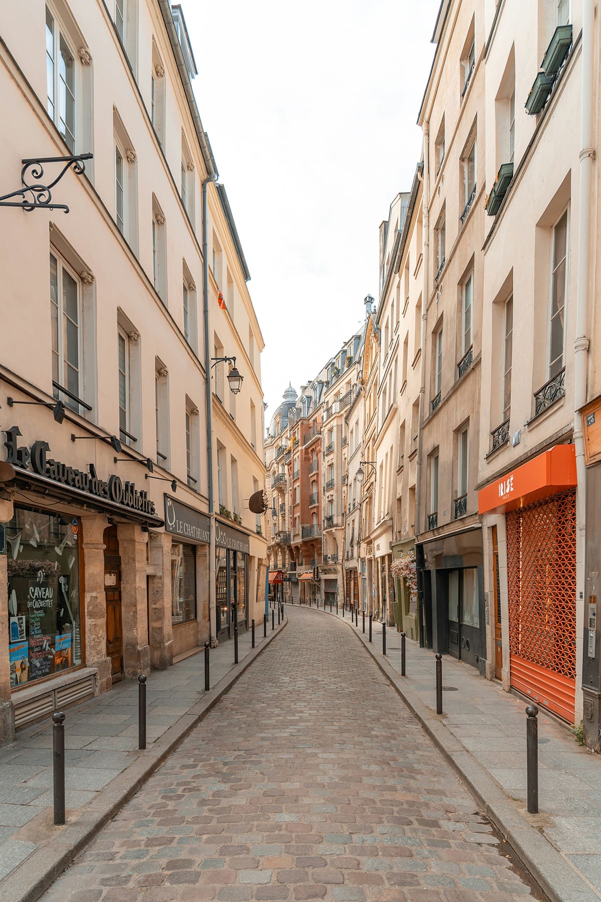 Quiet cobblestone street in Le Marais Paris with historic buildings and shops