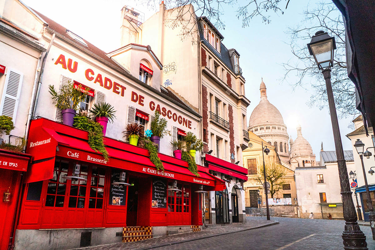 Colorful cafe in Montmartre Paris with Sacre Coeur Basilica in the background