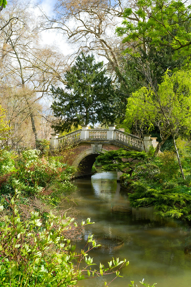 Bridge over water in Parc des Buttes-Chaumont with greenery in Paris