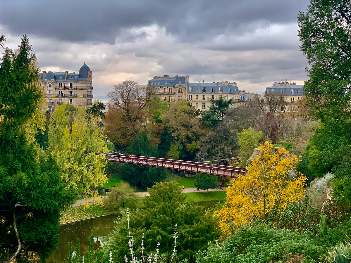 Landscape view of Parc des Buttes-Chaumont with trees and lake in Paris