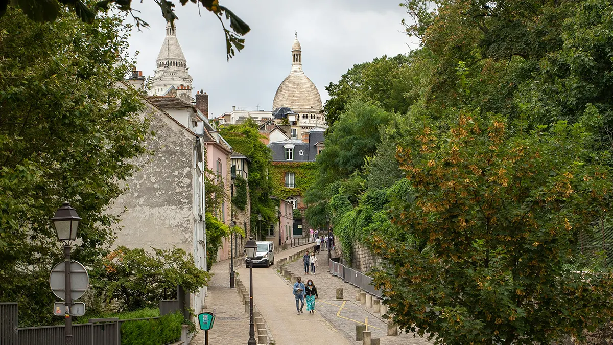 Sloping Montmartre street leading toward Sacré-Cœur through trees