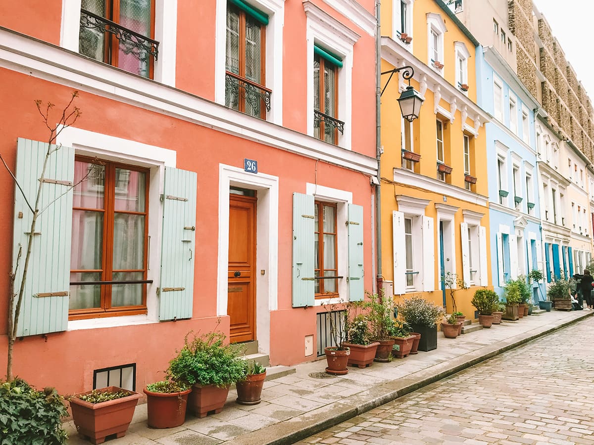 Row of colorful houses on Rue Crémieux Paris with flowers and cobblestone street