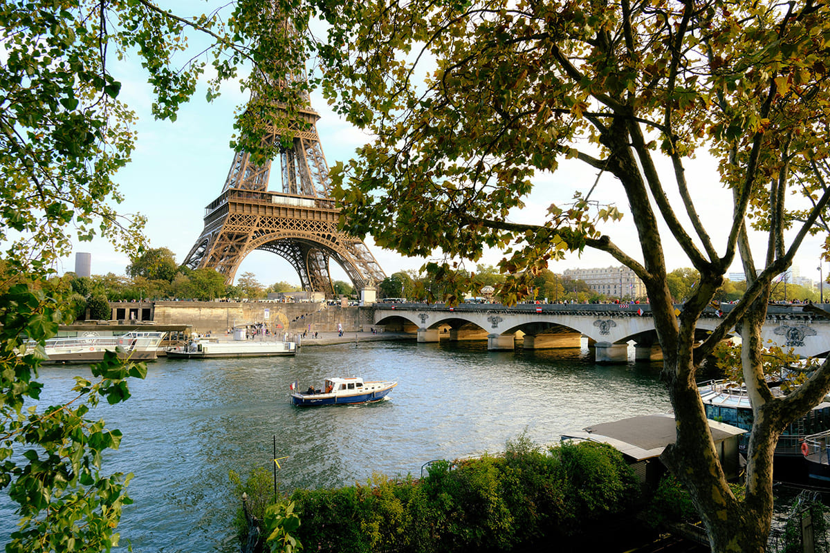 Eiffel Tower view from Seine River cruise with bridge and trees in Paris
