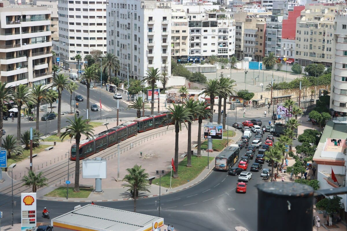 Red tram passing through a palm-lined junction in central Casablanca
