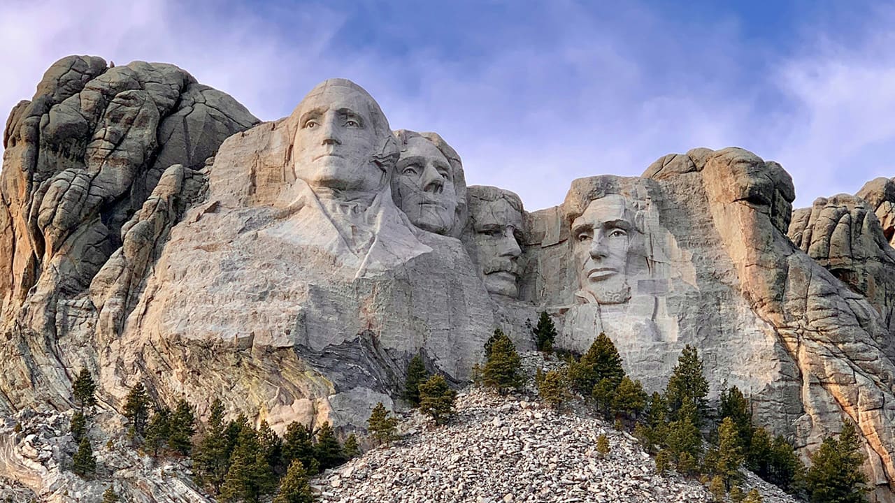 A detailed close-up shot of the granite faces of George Washington, Thomas Jefferson, Theodore Roosevelt, and Abraham Lincoln.