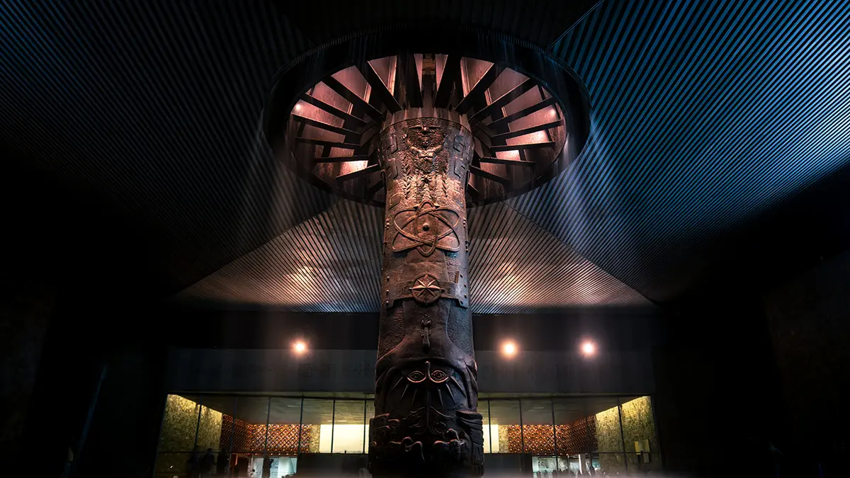 Columna esculpida e iluminada bajo la cubierta del patio del Museo Nacional de Antropología.