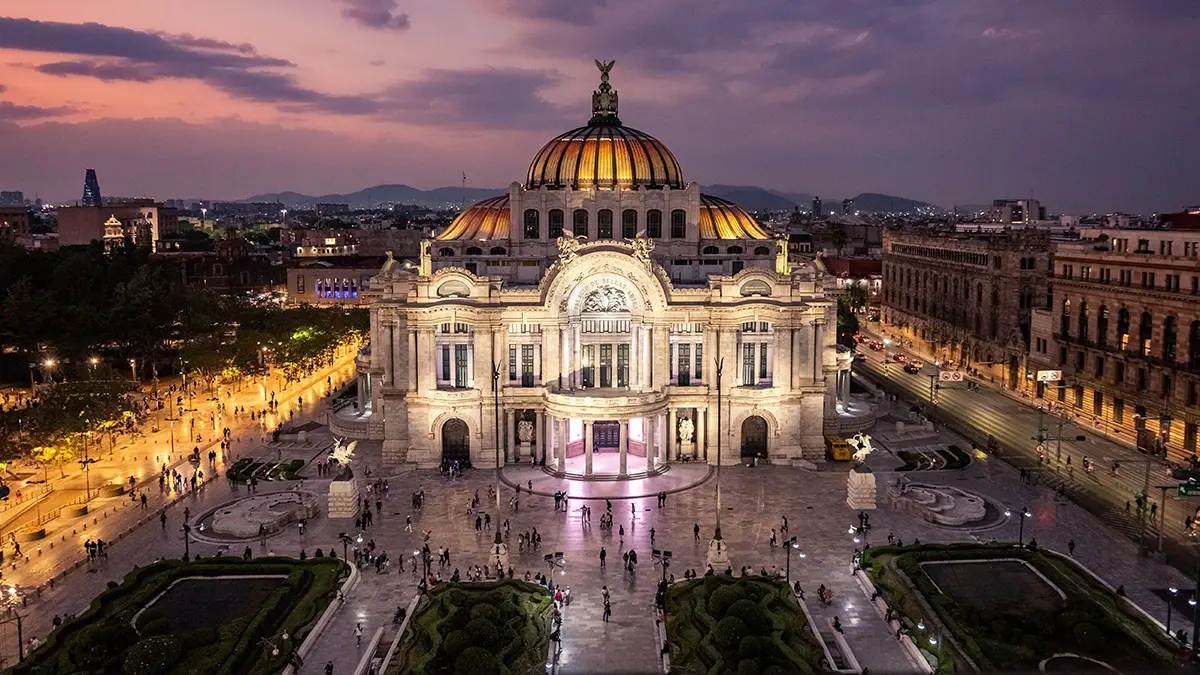 Palacio de Bellas Artes iluminado y su explanada al anochecer.