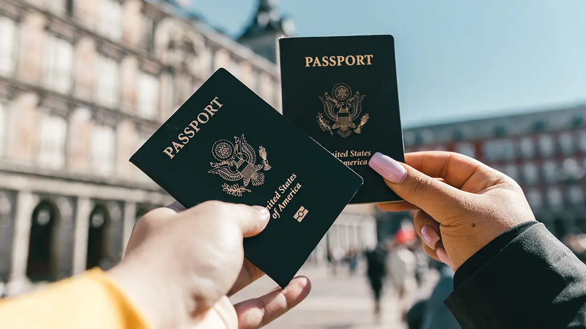 Two travelers holding passports together outdoors before an international trip