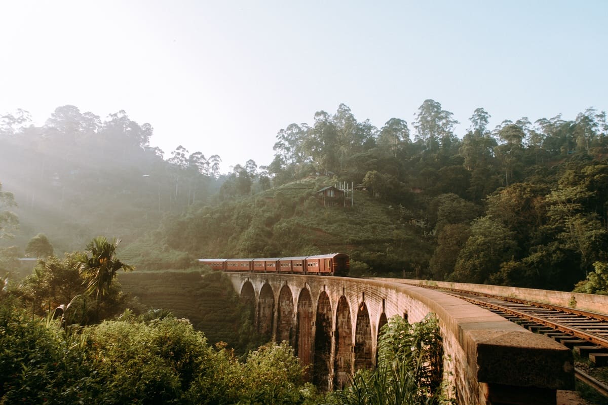 Tren de pasajeros cruzando el Puente de los Nueve Arcos entre las colinas verdes de Ella