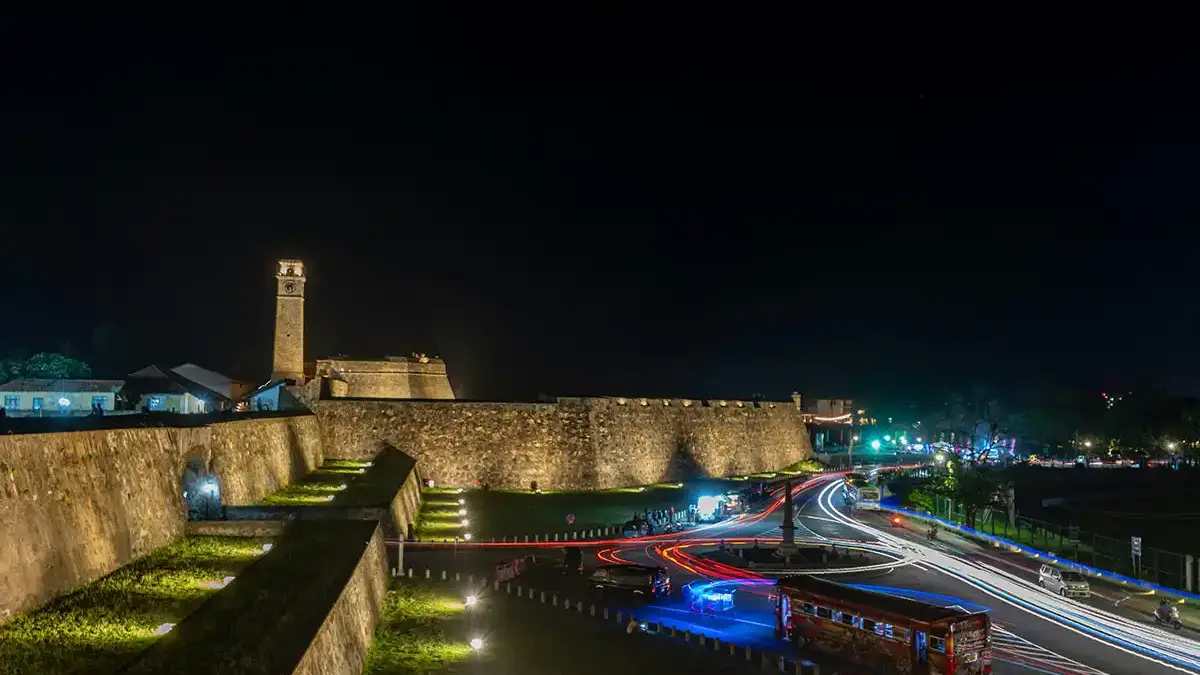 Murallas y Torre del Reloj de Galle Fort iluminadas junto al tráfico nocturno
