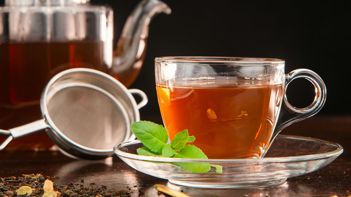 Taza y tetera de cristal con té negro preparado para una degustación