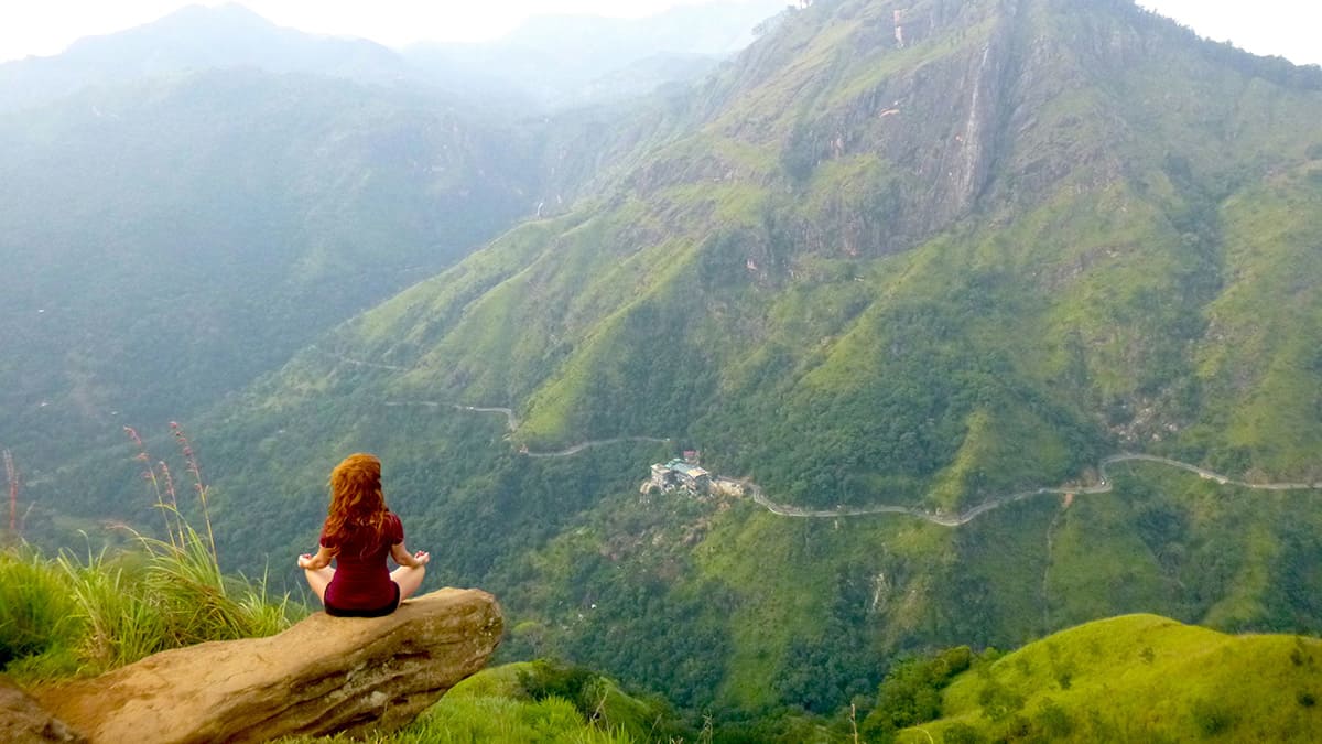 Viajera sentada frente a los valles verdes de la región montañosa de Sri Lanka