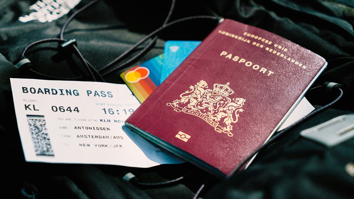 Una composición de viaje en la que se ven un pasaporte, una tarjeta de embarque y unas tarjetas de crédito sobre una maleta de viaje negra, que representa los preparativos para un viaje internacional y los requisitos de visado.