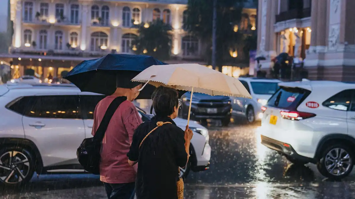 Travelers with umbrellas on a rainy evening in Thailand