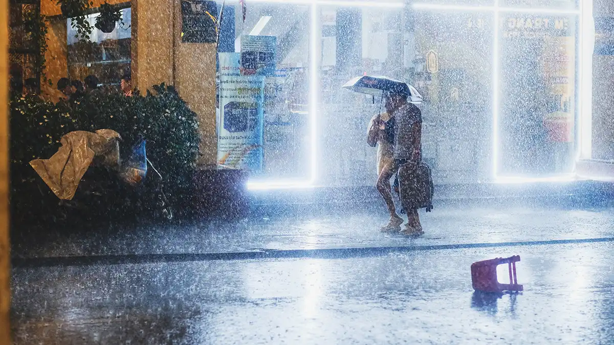 Traveler with umbrella during heavy rain in Thailand