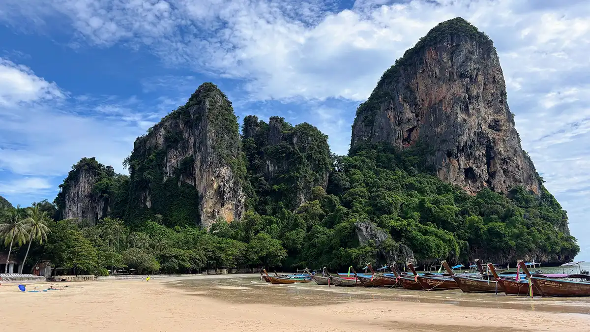 Longtail boats beneath limestone cliffs at Railay Beach in Krabi