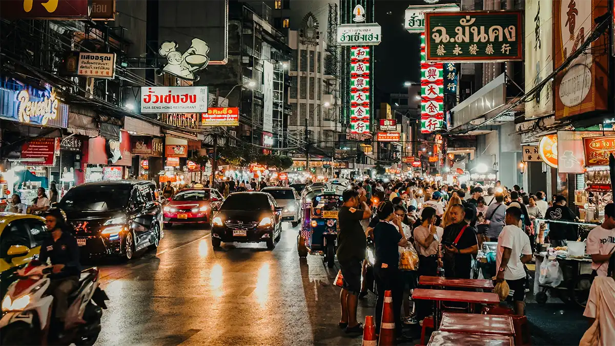 Traffic, pedestrians and buildings on a busy street in Bangkok