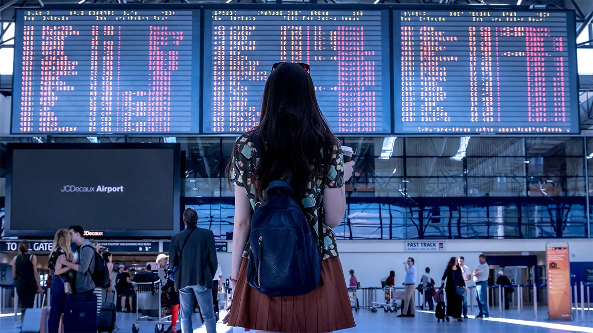 Traveler checking a flight information board at an airport in Thailand