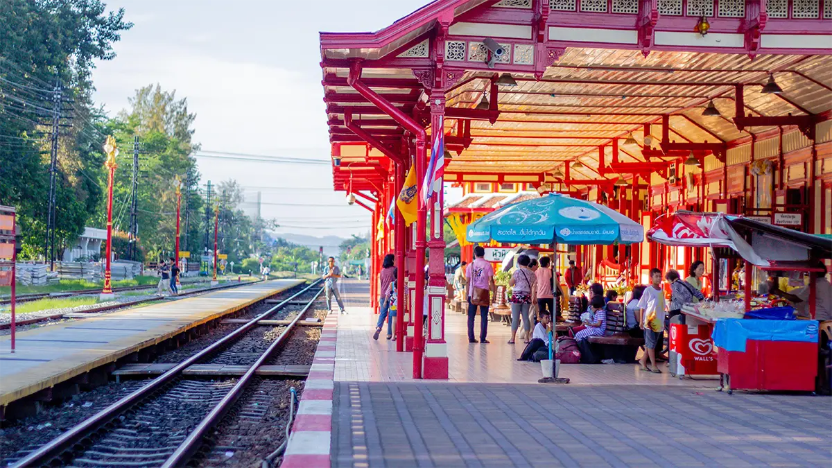 Long-distance passenger train waiting at a station platform in Thailand