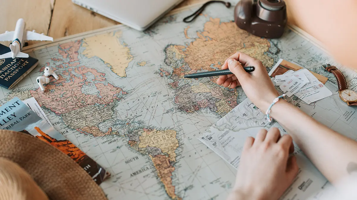 Traveler reviewing a world map with a passport and flight documents nearby