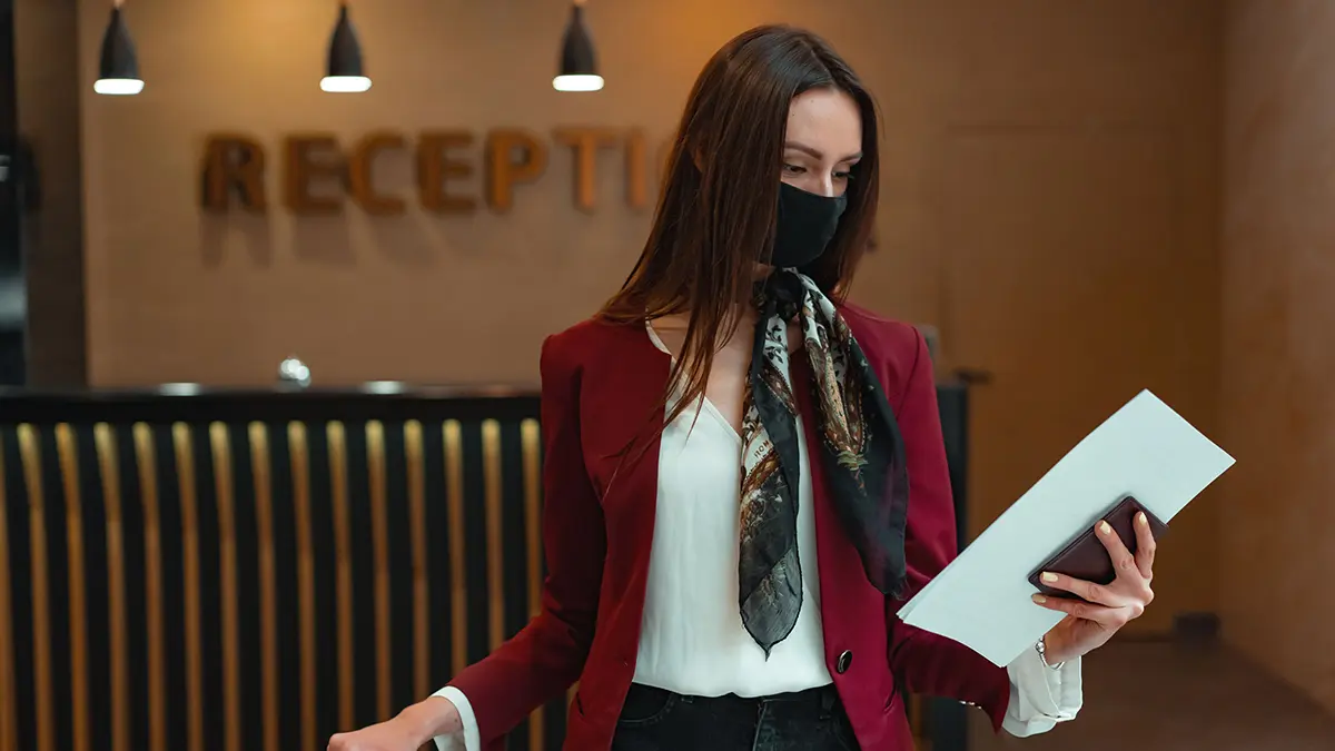 Traveler holding a passport and printed document at a reception desk