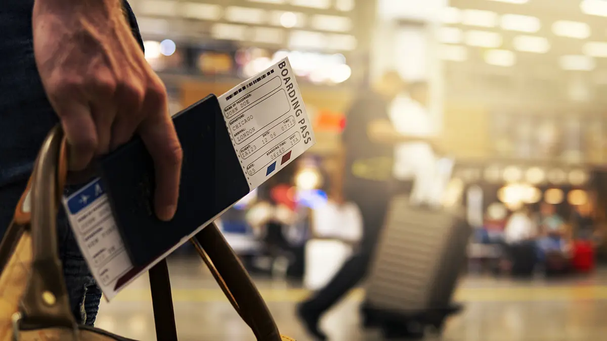 Traveler holding a passport and boarding pass inside an airport terminal