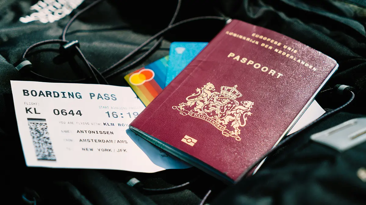 Passport and boarding pass beside a payment card and travel headphones